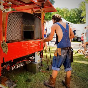 Rear view of man working on motorcycle against sky