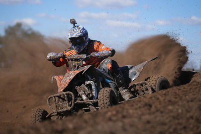 Racer riding quadbike in dirt during race