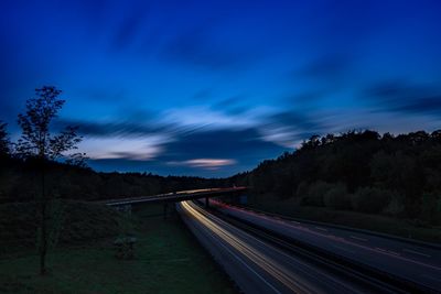 Light trails on road against sky at night