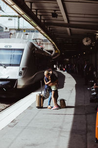 Happy mother and daughter embracing while greeting at railroad station