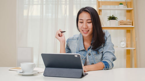 Young woman using laptop on table at home