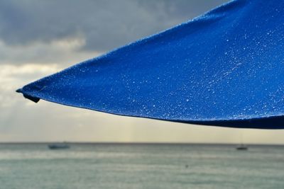 Close-up of blue parasol ans sea against sky