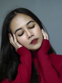 Close-up of beautiful woman with eyes closed against wall