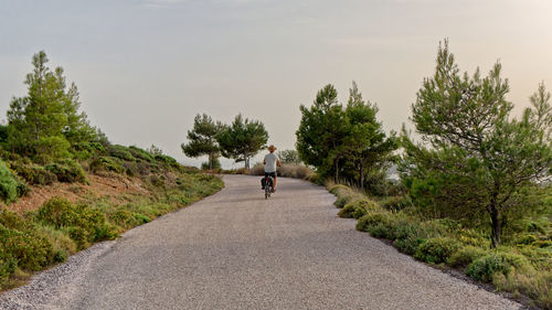 Rear view of man walking on road against sky