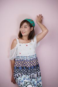 Portrait of a smiling young woman standing against wall