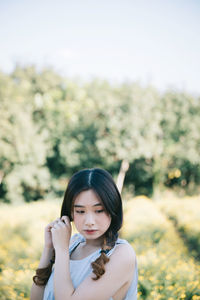 Portrait of young woman standing against plants