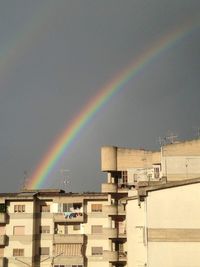 Rainbow over buildings in city against sky