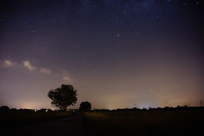 Silhouette trees on field against sky at night