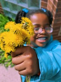 Close-up portrait of smiling woman with yellow flower