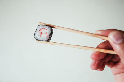 Close-up of hand holding ring over white background