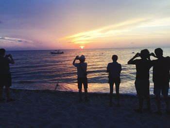 Silhouette of people on beach at sunset