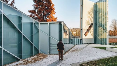 Rear view of man walking by building in city