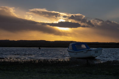 Boat moored in sea during sunset