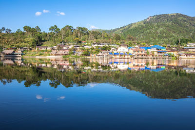 Scenic view of lake by buildings against sky