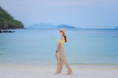 Full length of woman standing on beach against sky