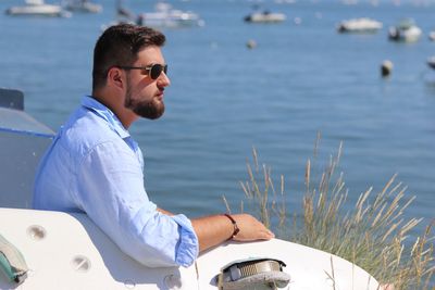 Side view of thoughtful man sitting by sea 