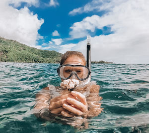 Portrait of woman holding coral in sea