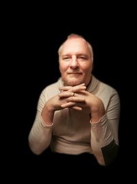 Portrait of smiling man against black background
