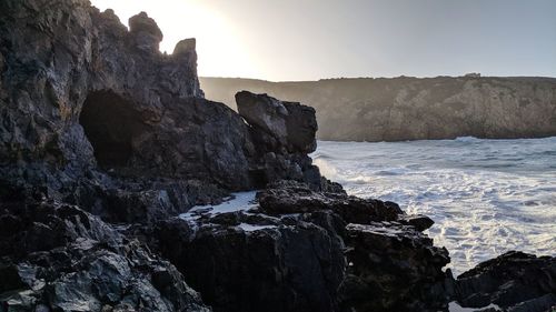 Rock formations on shore against clear sky