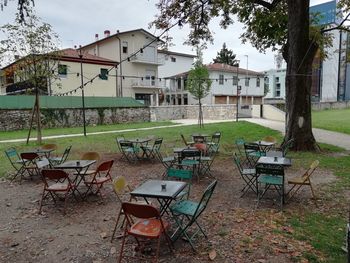 Empty chairs and table on field by building