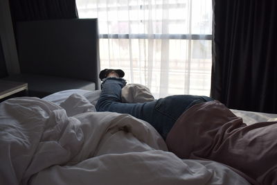 Low section of man relaxing on bed