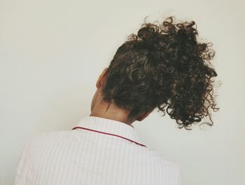 Rear view of woman with curly hair against white background