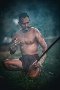 Portrait of shirtless man holding camera