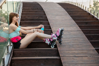 Full length of young woman sitting on staircase