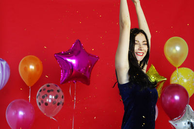 Full frame shot of young woman with red balloons against wall