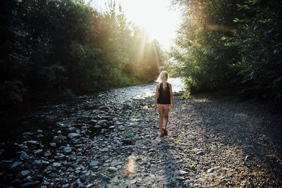 Rear view of carefree girl walking towards river in forest