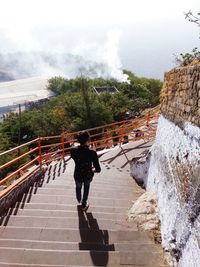 Full length rear view of man walking on steps