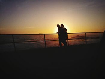 Silhouette man standing on beach against clear sky during sunset