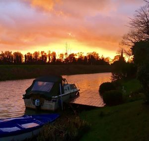 Boat moored on lake against sky during sunset