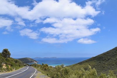 Scenic view of road by sea against sky