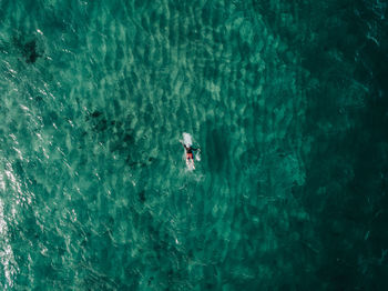 Aerial view of man lying on surfboard in sea