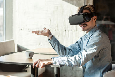 Man wearing virtual reality simulator while sitting at cafe
