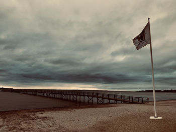 Flag on bridge over sea against sky