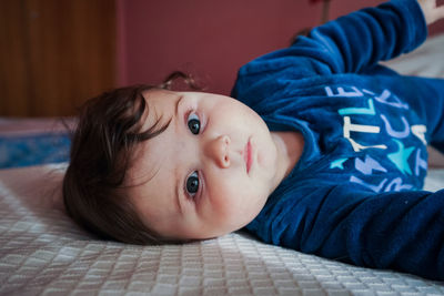 Portrait of cute baby lying on bed at home