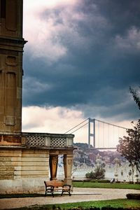 Gazebo on bridge in city against cloudy sky
