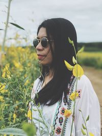 Young woman wearing sunglasses and red flowering plants