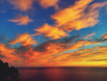 Scenic view of sea against cloudy sky during sunset