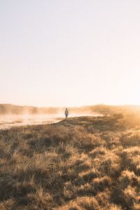 Man on field against sky during sunset