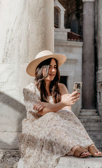 Young woman using mobile phone while sitting outdoors