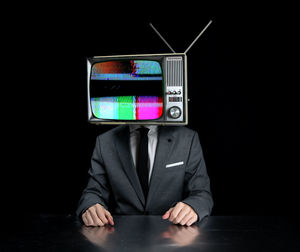 Midsection of man using phone while standing against black background