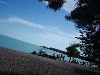 People on beach against blue sky