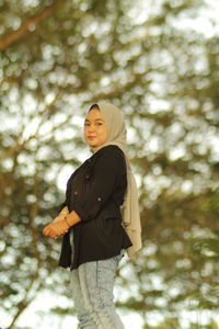 Low angle view of woman standing against trees