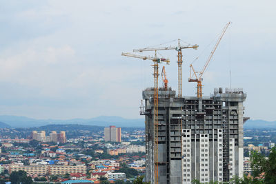 Cranes in city against sky