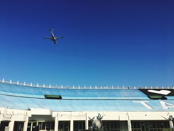 Low angle view of airplane flying against clear blue sky