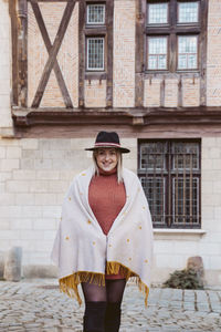 Portrait of woman standing against house