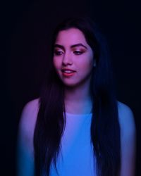 Portrait of beautiful young woman against black background